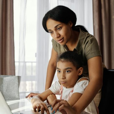 A mother helps her daughter with online learning at home, fostering education and togetherness.
